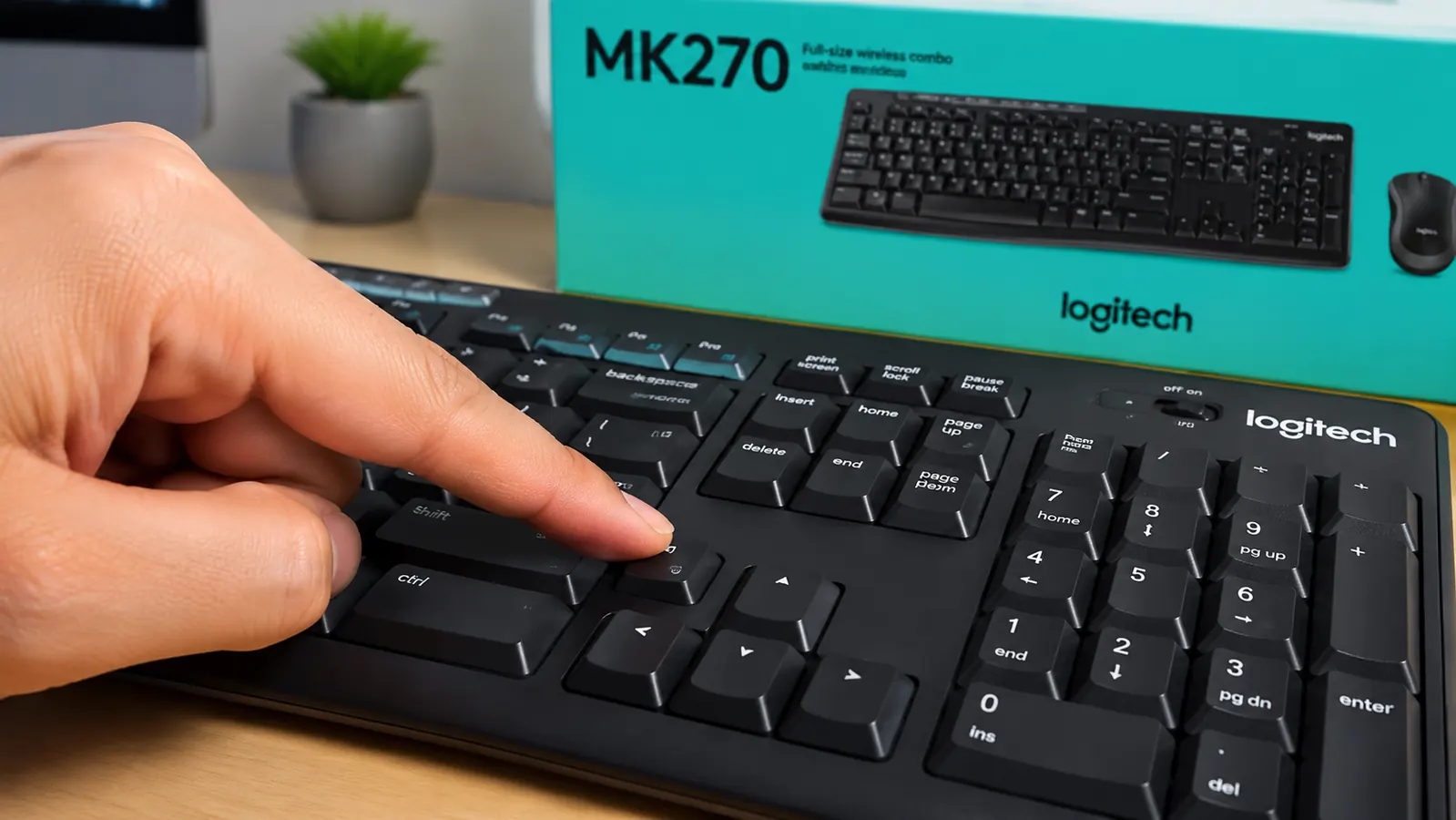 Close-up of a hand pressing a key on the Logitech MK270 keyboard, showing the low-profile membrane keycap and soft travel